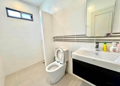 Modern bathroom with toilet, sink, mirror, and toiletries