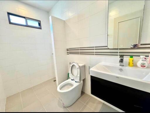 Modern bathroom with toilet, sink, mirror, and toiletries