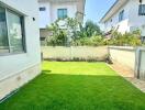 View of a green backyard with neighboring houses