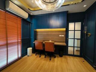 Home office with two desks, chairs, and a chandelier