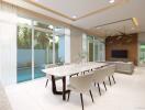 Modern dining area leading into a stylish living room with pool view