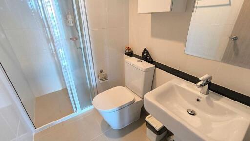 Modern bathroom with glass shower, sink, and toilet