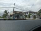 Street view of a residential area with a house and a small shop