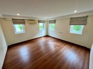 Spacious bedroom with wooden flooring and ample natural light