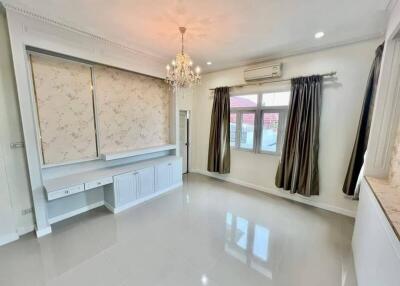 Spacious living room with chandelier, curtains, and built-in storage