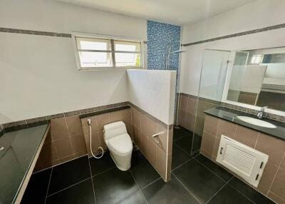 Modern bathroom with black tiles, glass shower, and toilet