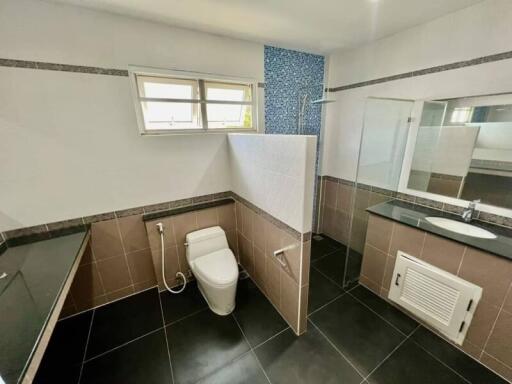 Modern bathroom with black tiles, glass shower, and toilet