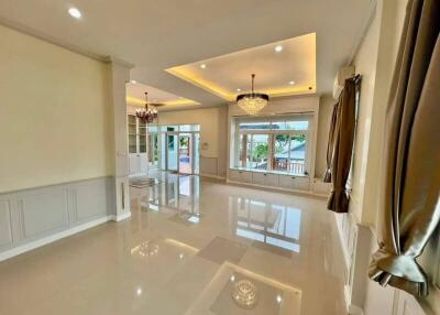 spacious and elegant living area with chandeliers and large windows