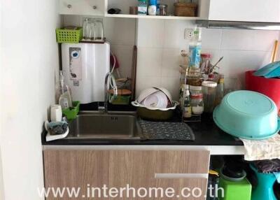 Small kitchen area with sink, shelves, and storage