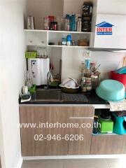 Small kitchen area with sink, shelves, and storage