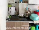 Small kitchen area with sink, shelves, and storage