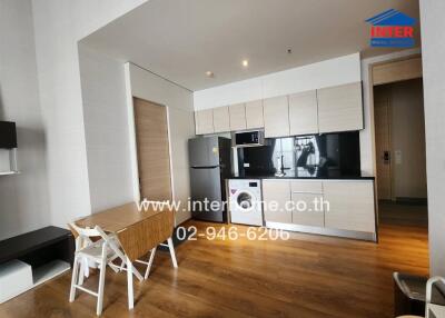 Modern kitchen with dining area, wooden flooring, fridge, microwave, and washing machine