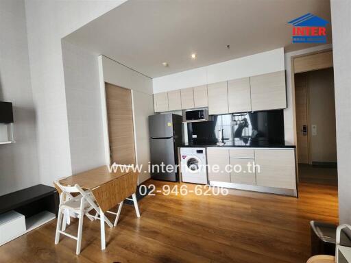 Modern kitchen with dining area, wooden flooring, fridge, microwave, and washing machine