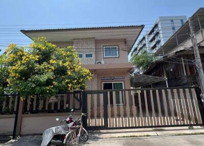 Front view of a two-story house with a bike and a covered motorbike in the driveway