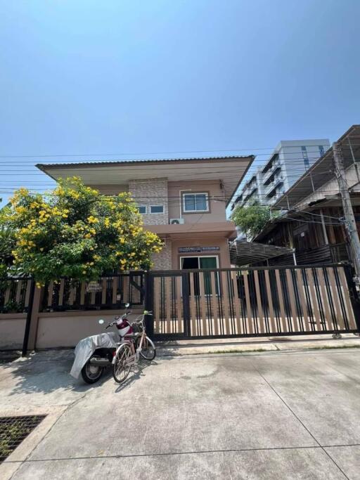 Front view of a two-story house with a bike and a covered motorbike in the driveway