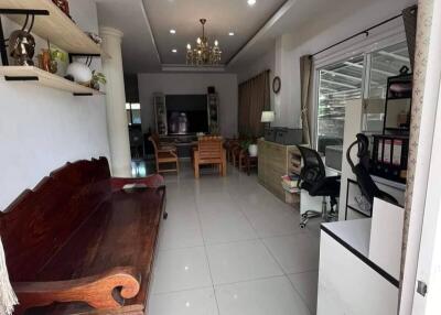 Spacious living room with tiled floors, built-in shelves, wooden bench, chandelier, and ample natural light