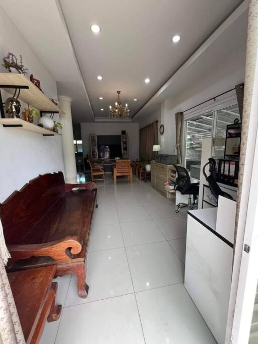 Spacious living room with tiled floors, built-in shelves, wooden bench, chandelier, and ample natural light