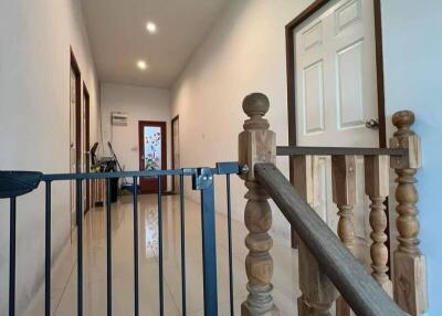 Well-lit corridor with wooden stair railing and baby gate