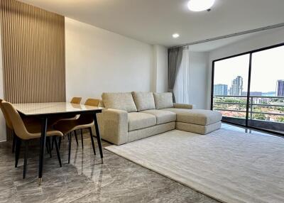 Living room with a large window, sofa, dining table, and chairs