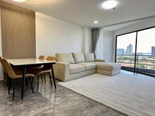 Living room with a large window, sofa, dining table, and chairs