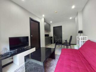 Modern living room with red sofa, black coffee table, TV, and dining area