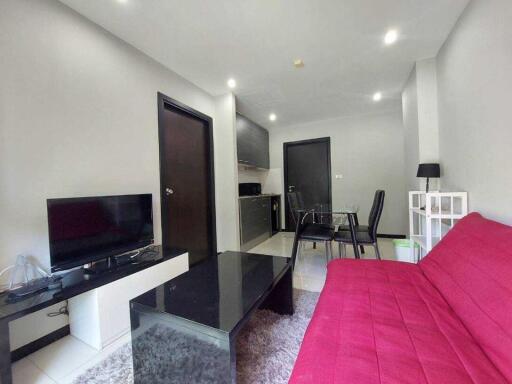 Modern living room with red sofa, black coffee table, TV, and dining area