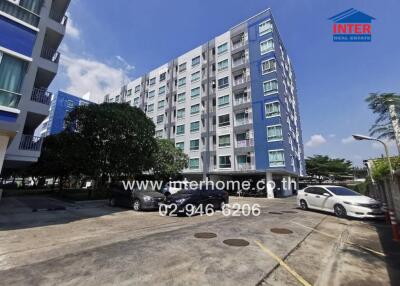 Exterior view of a multi-story residential building with parking area