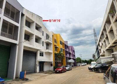 Row of buildings with colorful facades, parked cars, and overcast sky