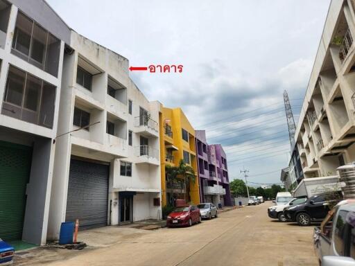 Row of buildings with colorful facades, parked cars, and overcast sky