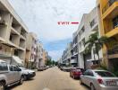 Street view of a residential area with multiple buildings and parked cars