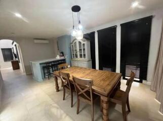 Spacious dining room with wooden table and chairs, modern lighting, and large windows.