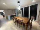 Spacious dining room with wooden table and chairs, modern lighting, and large windows.