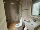 Modern bathroom with neutral tile walls, glass shower enclosure, toilet, sink, and a window with blinds