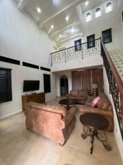 Spacious living room with high ceilings, balcony view, and modern furniture