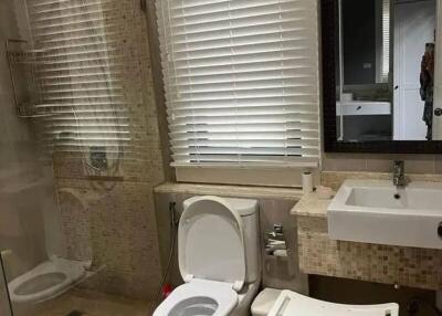 Modern bathroom with glass shower, toilet, sink, and seating stool