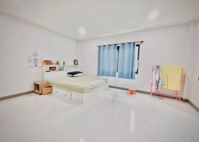 Bright and spacious bedroom with a bed, blue curtains, and a clothes rack