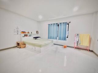 Bright and spacious bedroom with a bed, blue curtains, and a clothes rack