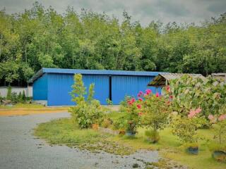 Exterior view of property with garden and blue storage buildings