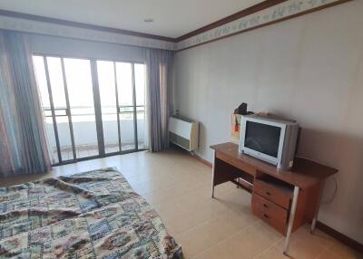 Bedroom with a bed, TV, desk, and sliding glass doors leading to a balcony