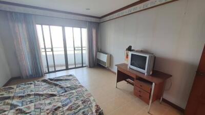 Bedroom with a bed, TV, desk, and sliding glass doors leading to a balcony