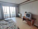 Bedroom with a bed, TV, desk, and sliding glass doors leading to a balcony