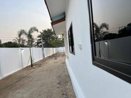 Side exterior view of a house with white walls and a garden space