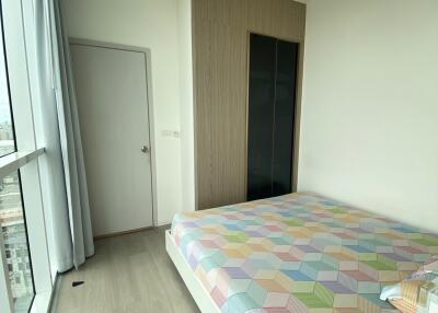 Small bedroom with a large window and patterned bed cover