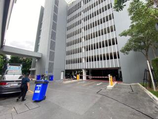 Exterior view of a multi-storey parking building with a person and a recycling bin