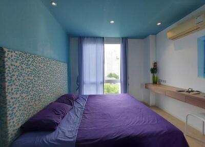 Bright bedroom with blue ceiling and purple bedding