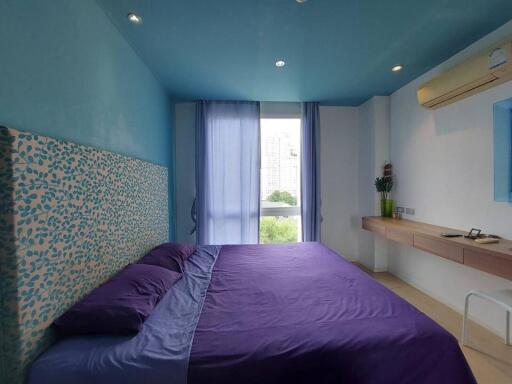 Bright bedroom with blue ceiling and purple bedding