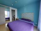 Bedroom with blue walls and purple bedding