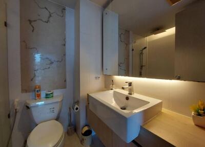 Modern bathroom with toilet, sink, large mirror, and shower