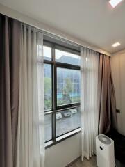 Bedroom window with curtains and a view of an outside parking area