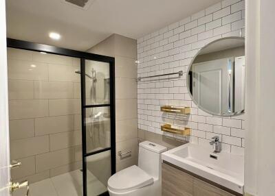 Modern bathroom with glass shower, round mirror, and elegant fixtures